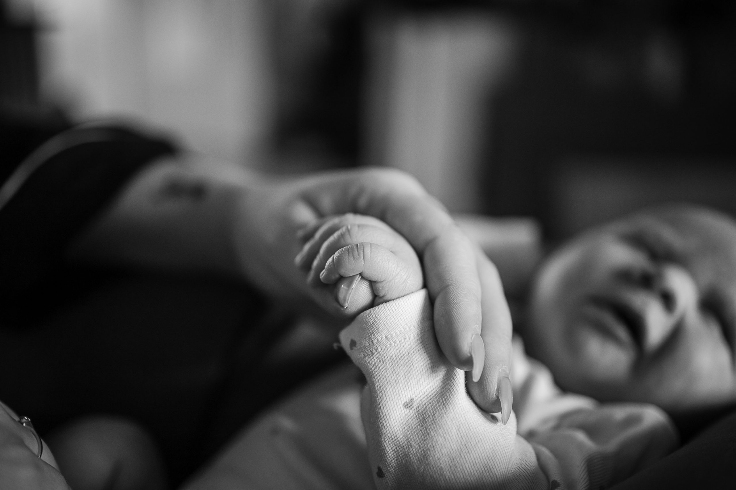 Nyfött barn håller om mammans finger.